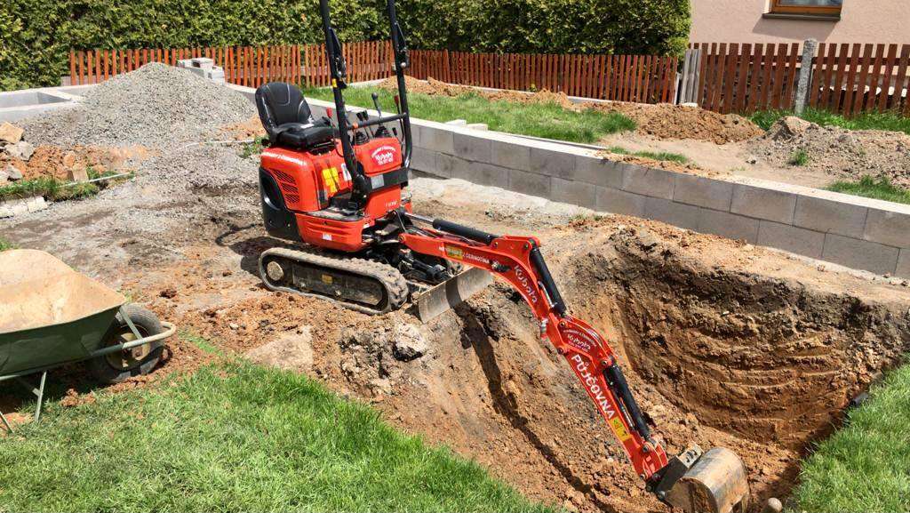 Minibagr Kubota při výkopu na zahradě
